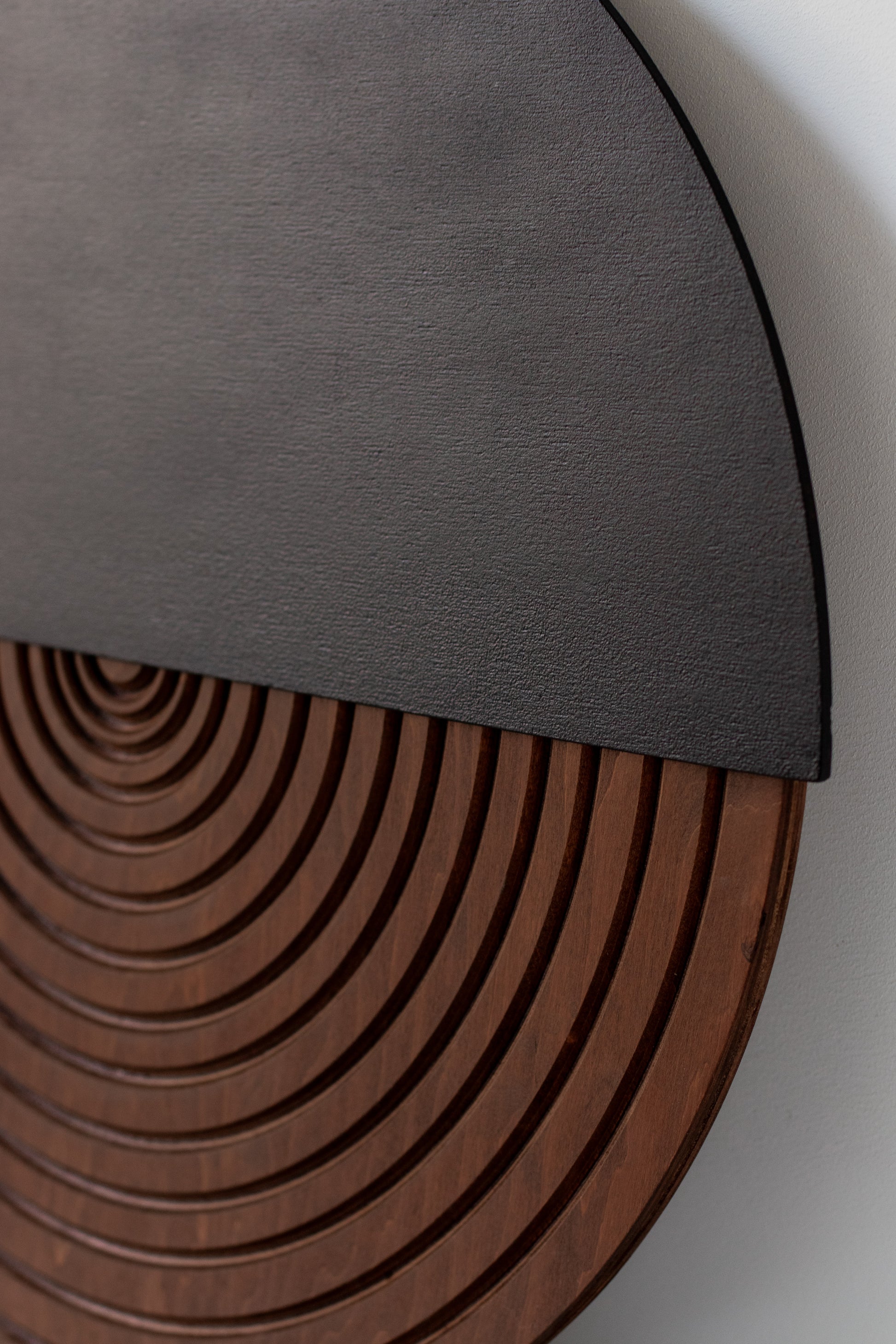 Close-up of a circular wooden product with concentric circles and a black top 