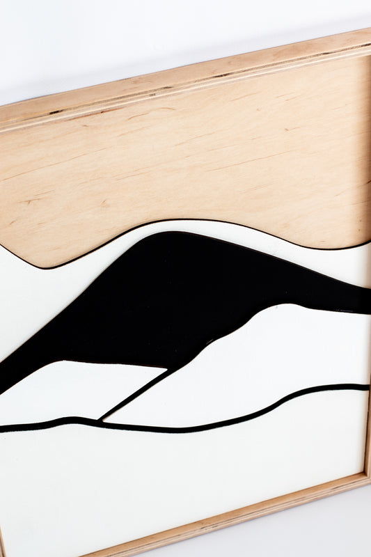 Abstract black line art on a white background with a wooden frame.